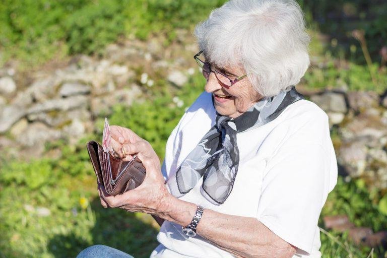 mujer jubilada con un billete y su cartera en la mano